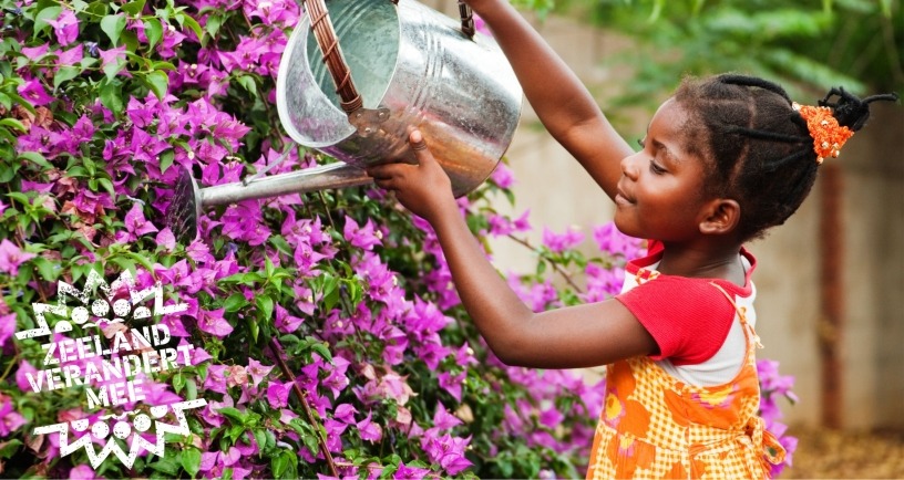 Meisje geeft bloemen water met gieter