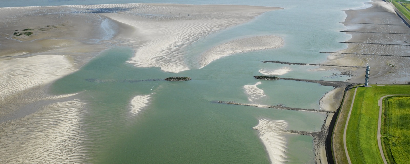 luchtfoto van de Westerschelde met radartoren, strekdammen en de zandplaat bij Ossenisse
