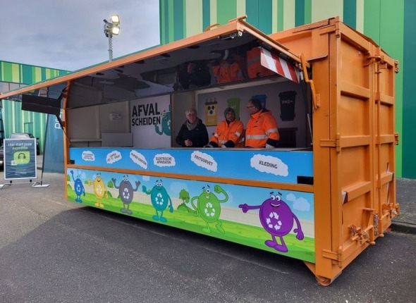 Een vrolijk gekleurd gedecoreerde container met een geïntegreerde balie waar gemeentemedewerkers afval inzamelen. 