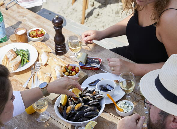 Genieten van mosselpannetje aan tafel op het strand. Beeld: Nederlands Mosselbureau
