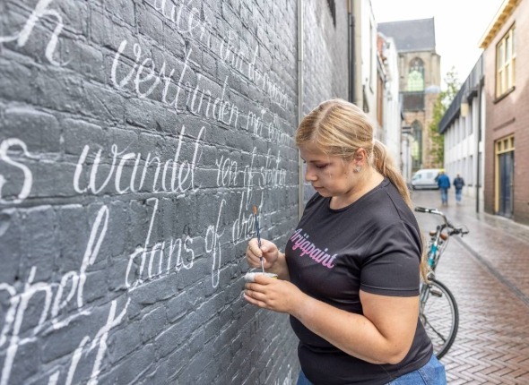 Vrouw schrijft gedicht op muur