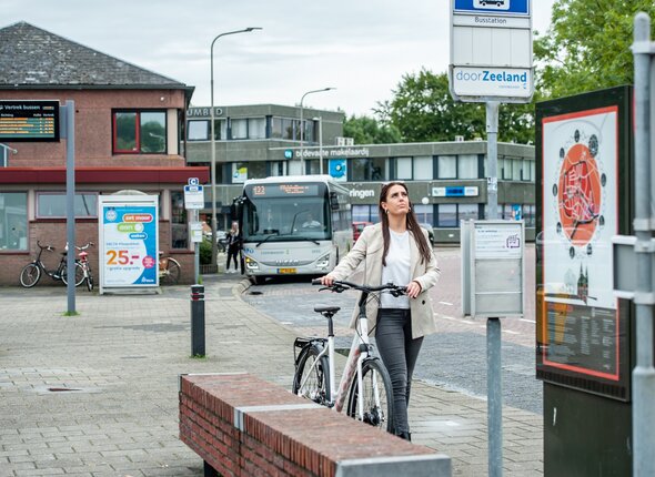 Mevrouw met een deelfiets bij het busstation