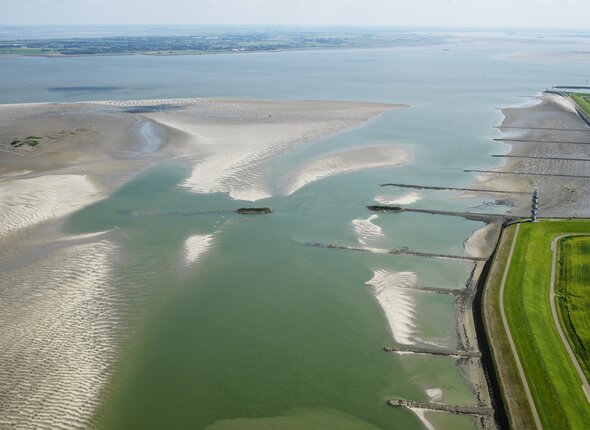 luchtfoto van de Westerschelde met radartoren, strekdammen en de zandplaat bij Ossenisse