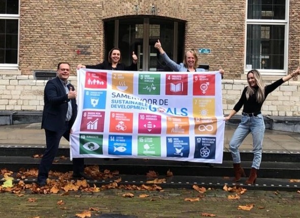 Collega's van Inkoop vieren de winst met de SDG vlag!