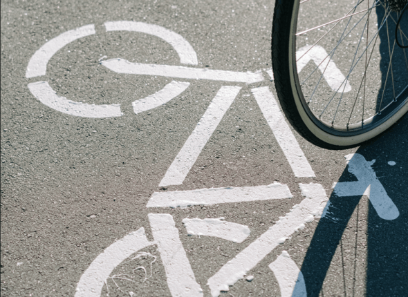 een gedeelte van een fietswiel in beeld en het asfalt van het fietspad