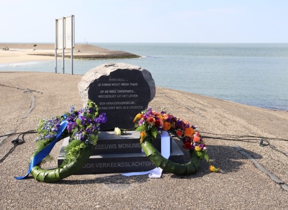 Zeeuws monument voor verkeersslachtoffers op Neeltje Jans, een steen met een gedicht erop en twee bloemenkransen