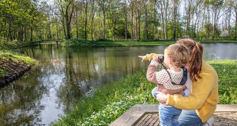 Moeder en kind bekijken natuur via verrekijker