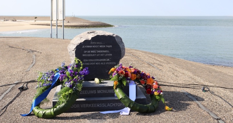 Zeeuws monument voor verkeersslachtoffers op Neeltje Jans, een steen met een gedicht erop en twee bloemenkransen