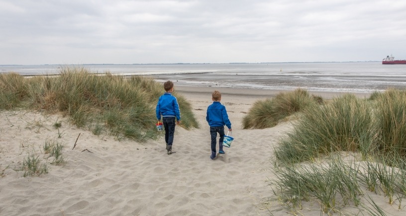 2 kinderen met emmer lopen door duinen van strand 'de Kaloot' bij Borssele