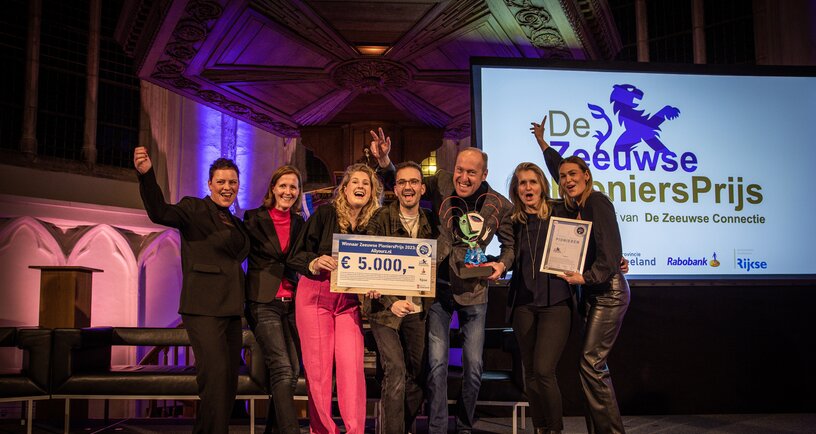 Winnaars Pioniersprijs 2023 op het podium. Ze houden cheque van 5000 euro vast.