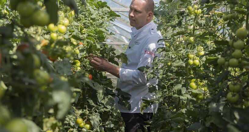 Kok Eric van Bochove keurt de tomaten die hij in een gerecht wil verwerken bij de lokale kweker