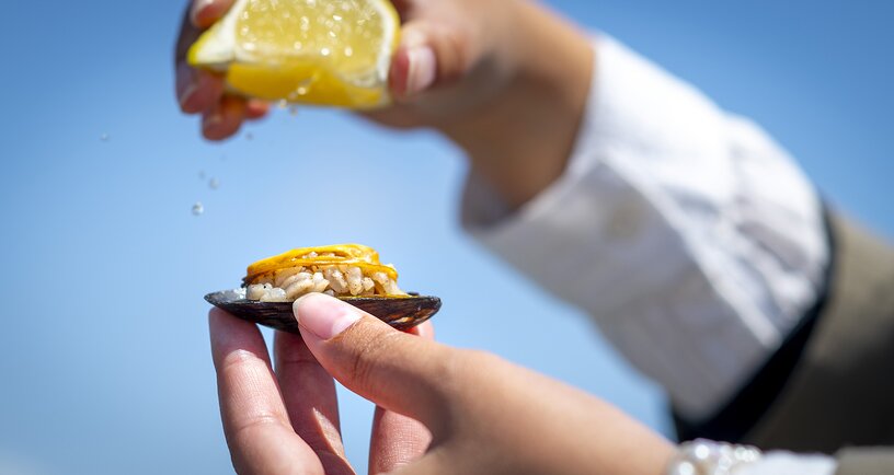 De Limoen uitknijpen over een loaded mossel: een met gekruide rijst gevulde Zeeuwse mossel. Beeld: Nederlands Mosselbureau