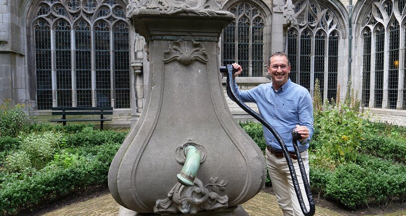 Ronnie Hollebrandse bij de oude waterpomp in de Kloostertuin van de Abdij