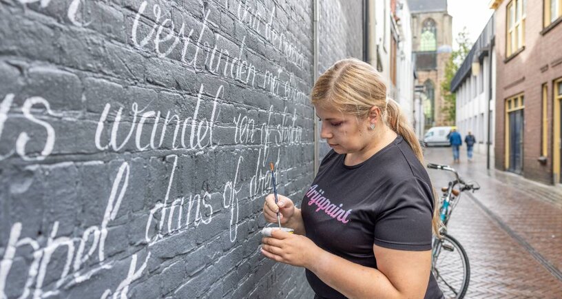 Vrouw schrijft gedicht op muur