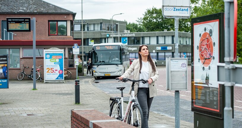 Mevrouw met een deelfiets bij het busstation