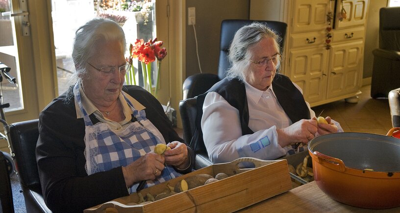 2 oudere vrouwen schillen aardappelen