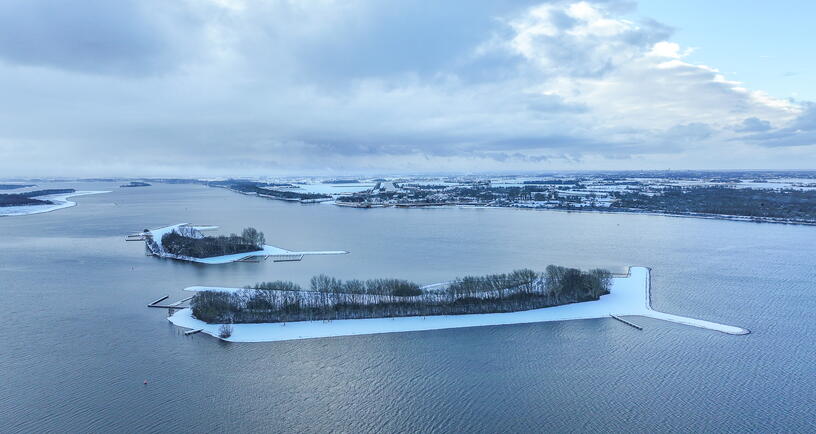 Luchtfoto Veerse Meer in de winter, met een laagje sneeuw op het land.