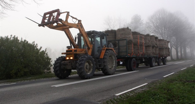 Landbouwvoertuig op de weg in de mist