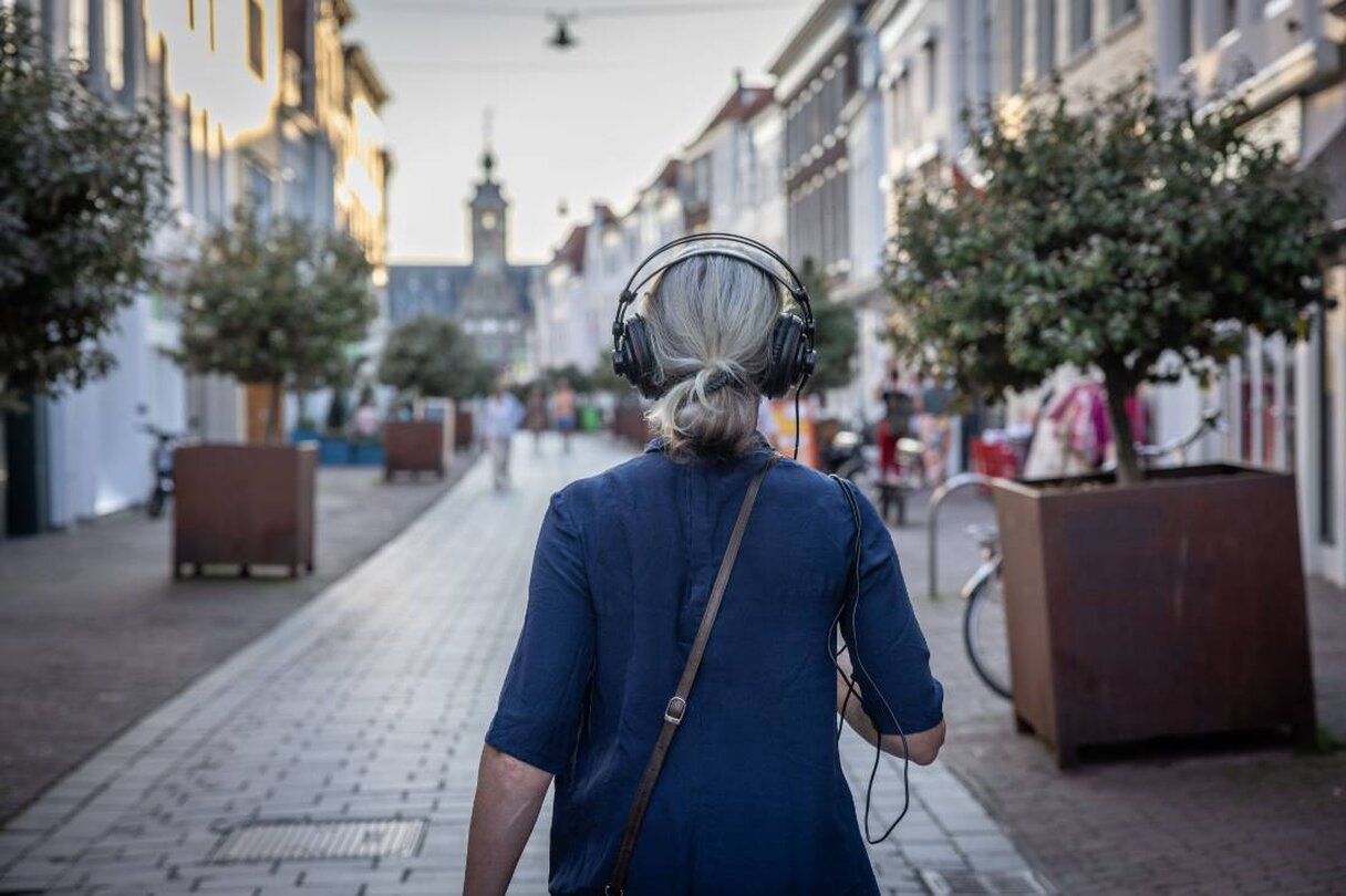 vrouw loopt met koptelefoon door de stad