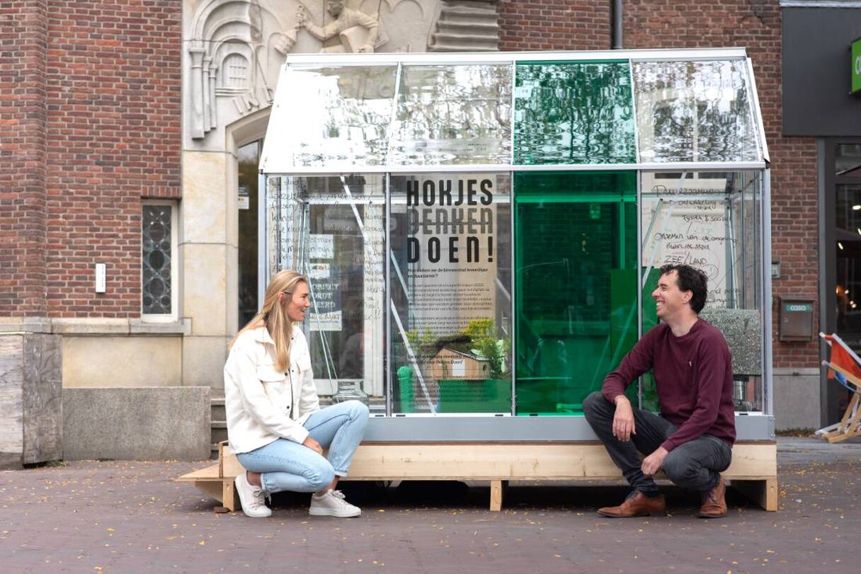 mensen zitten voor glazen kas