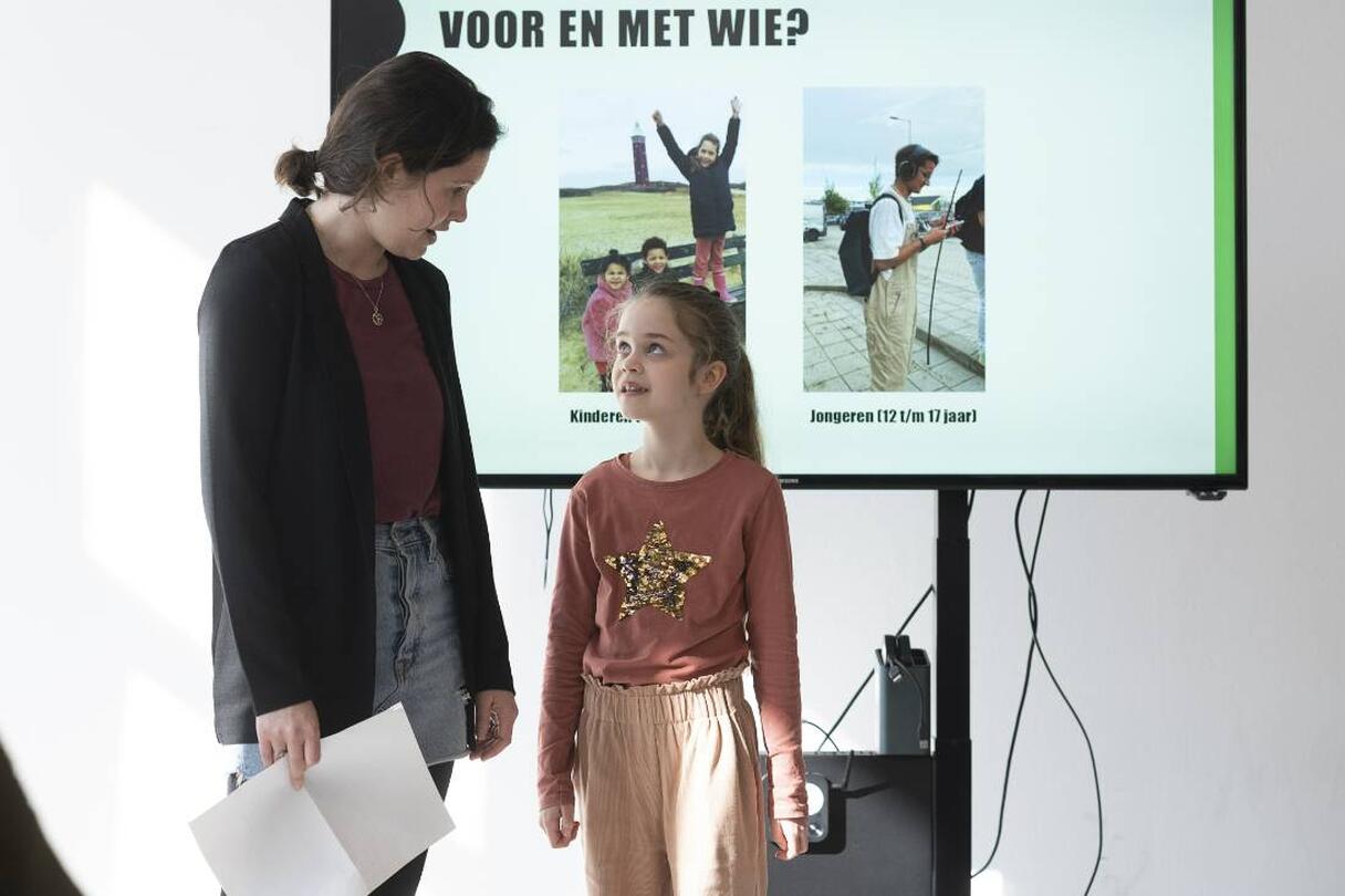 volwassene en kind kijken naar elkaar voor presentatiescherm