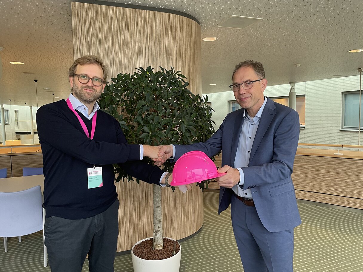 Edwin Prins overhandigt de roze bouwhelm aan de Thoolse wethouder Peter Hoek.