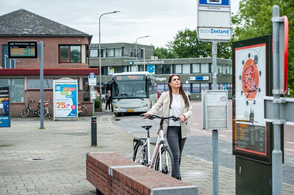 Mevrouw met een deelfiets bij het busstation