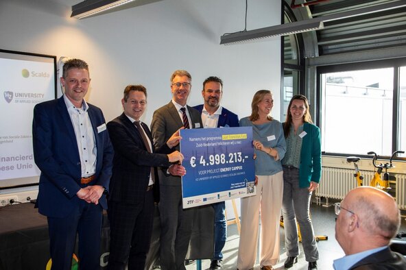 Gedeputeerden Joannes-de Bat en Harry van der Maas overhandigen een cheque aan projectleiders van het project Energy Campus