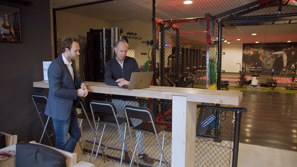 Twee mannen aan een statafel kijken naar laptop